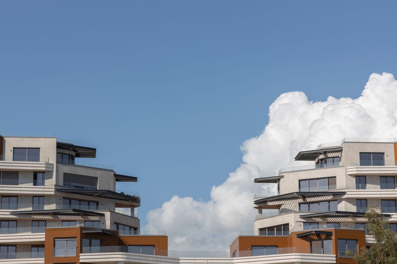 Services Contemporary urban architecture under a bright blue sky with clouds.